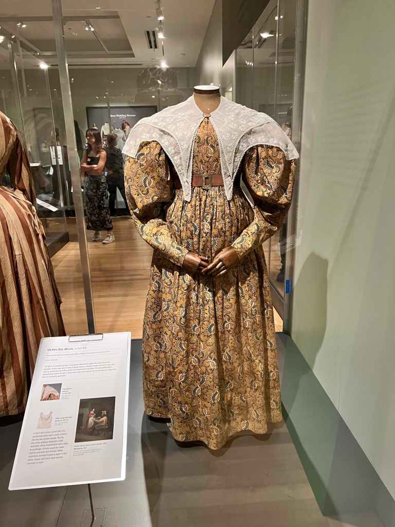 1830: Ocher calico day dress with gigot sleeves and embroidered cotton mull pelerine